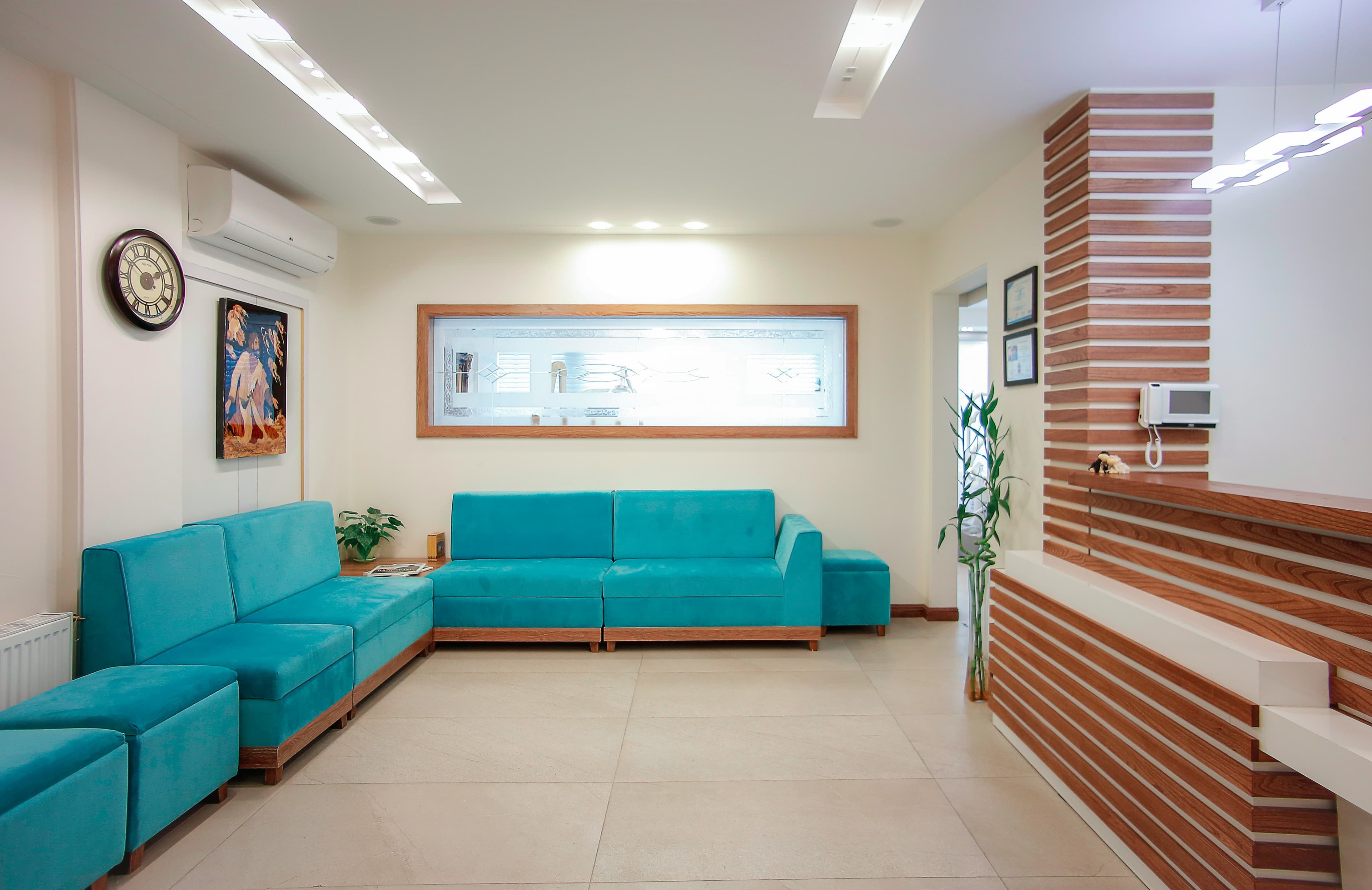 Modern reception area featuring turquoise sofas, wood-slatted walls, and a bright minimalist interior.