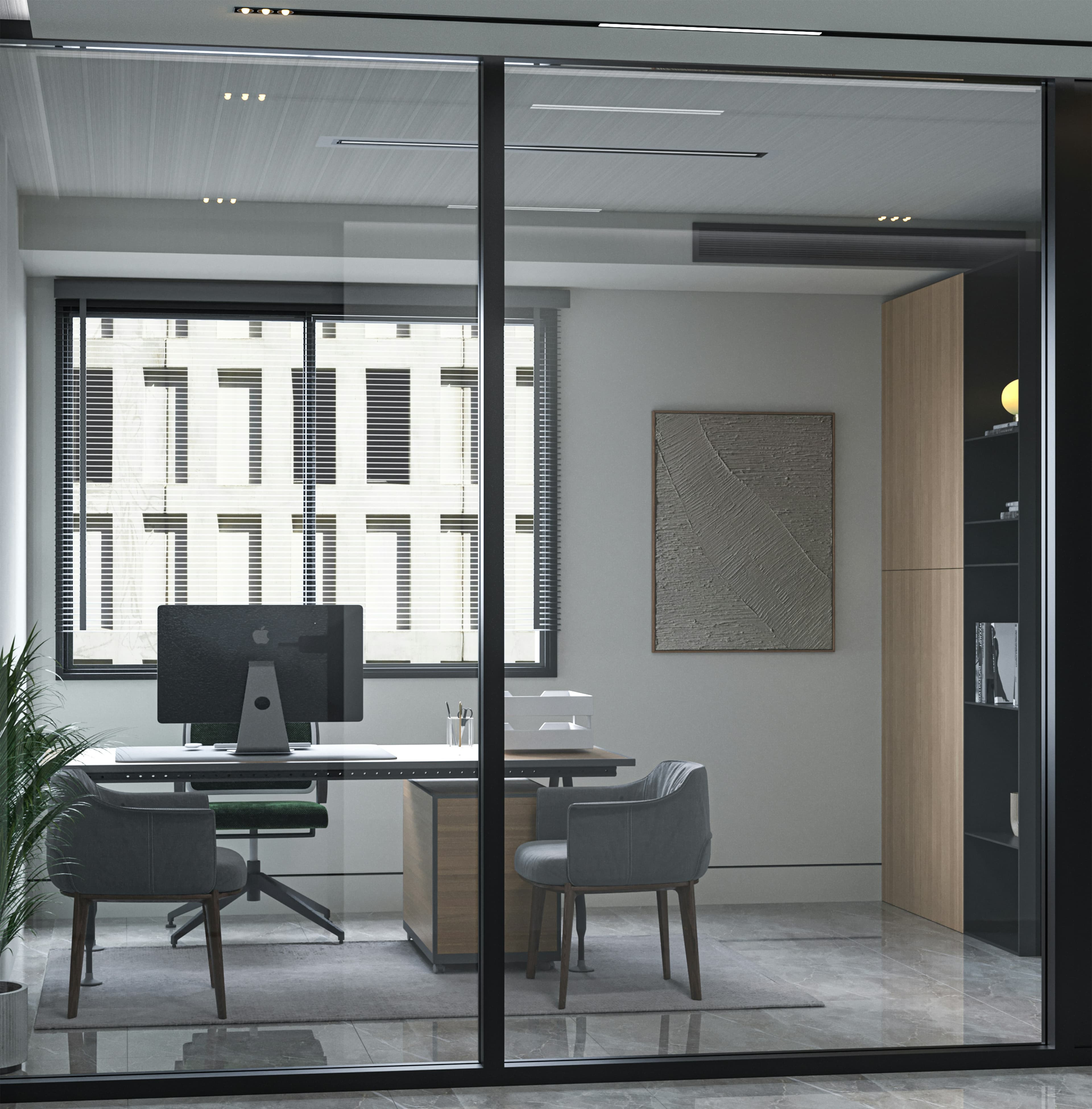 Modern office interior with a desk, computer, and grey chairs behind a glass partition.